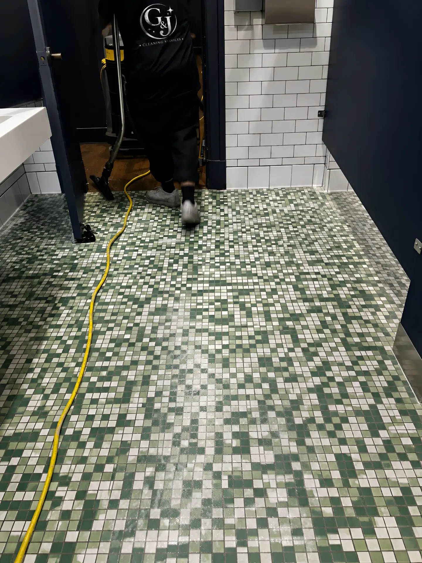 G&J Cleaning Services technician deep cleaning a mosaic restroom floor in National City, CA